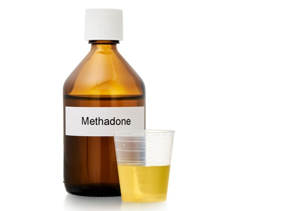 brown pharmacy bottle labeled "methadone" and dose cup filled with yellow liquid