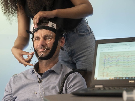 a person applying transcranial direct stimulation leads to a man's head