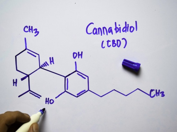 person drawing chemical symbol for CBD on a whiteboard