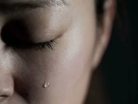 closeup of face with tear falling from closed eye