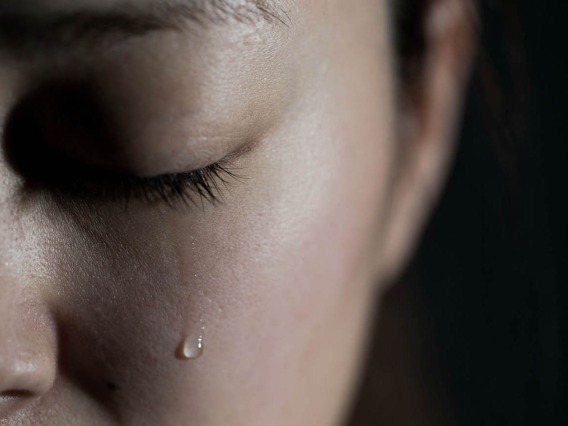 closeup of face with tear falling from closed eye