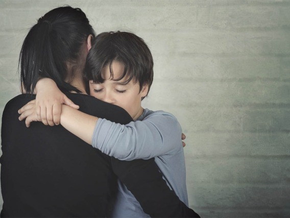 a woman hugs a young child looking sad