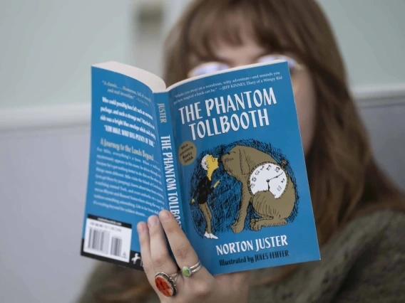 close up of book "The Phantom Tollbooth" being read by a person