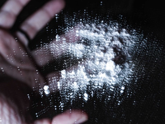 white powder on black mirror with hand in the background