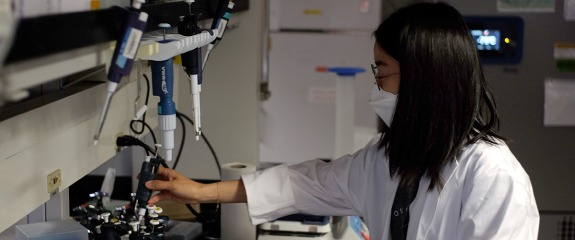 Research student handling lab equipment.