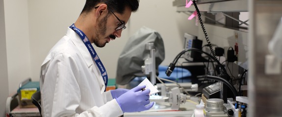 Student in lab coat reviewing test results.