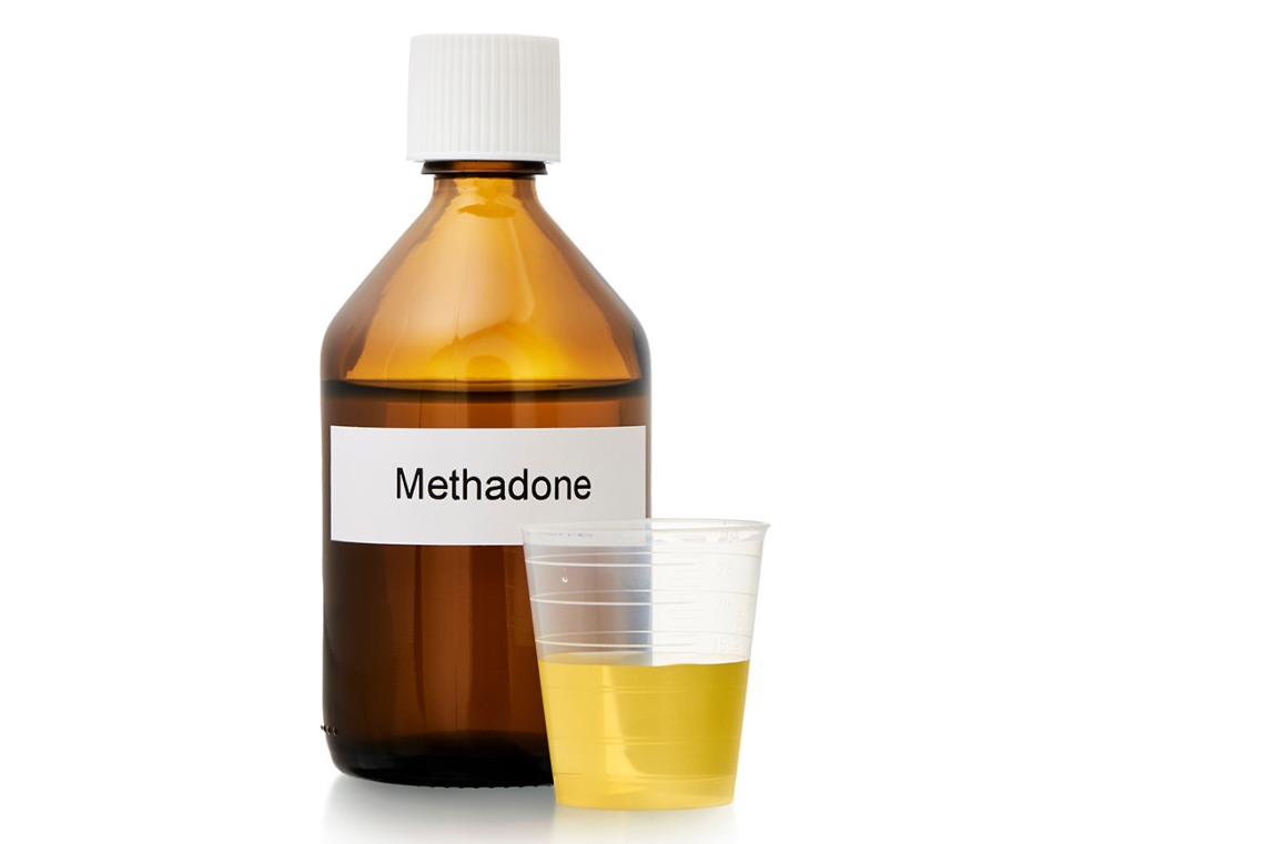 brown pharmacy bottle labeled "methadone" and dose cup filled with yellow liquid