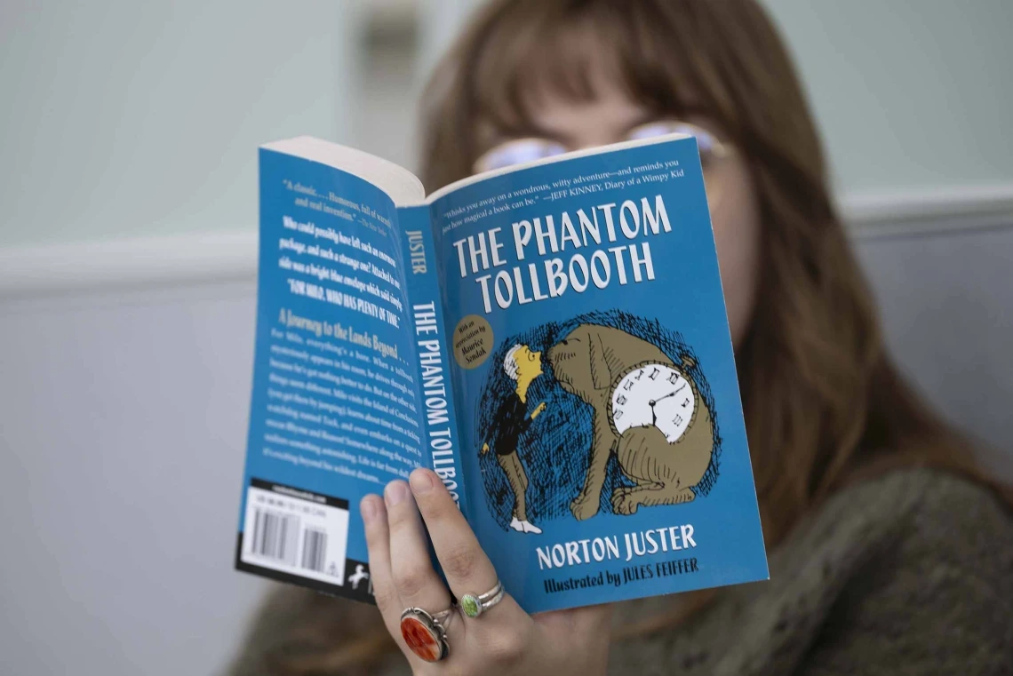 close up of book "The Phantom Tollbooth" being read by a person