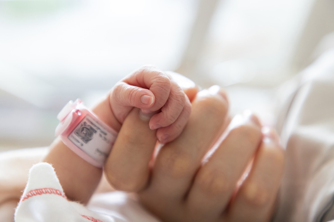 close up of infant hand holding onto mother's index finger