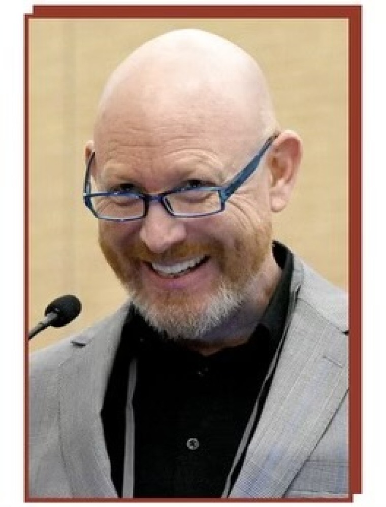 Dr. Franz Rischard, smiling, in front of a microphone